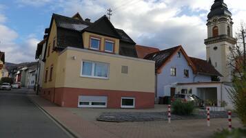 A two-story building with a garage, a church with a clock tower, and a clear sky.