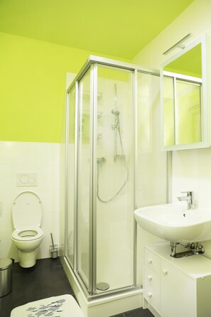 A bathroom with a glass-enclosed shower, a white sink, and a toilet.