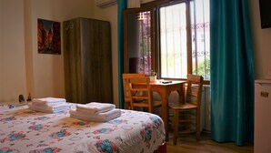 A hotel room with a bed, a desk, and a chair. There is a window with curtains, a painting on the wall, and a small refrigerator. - Halikarnas Butik Hotel (Adalar)