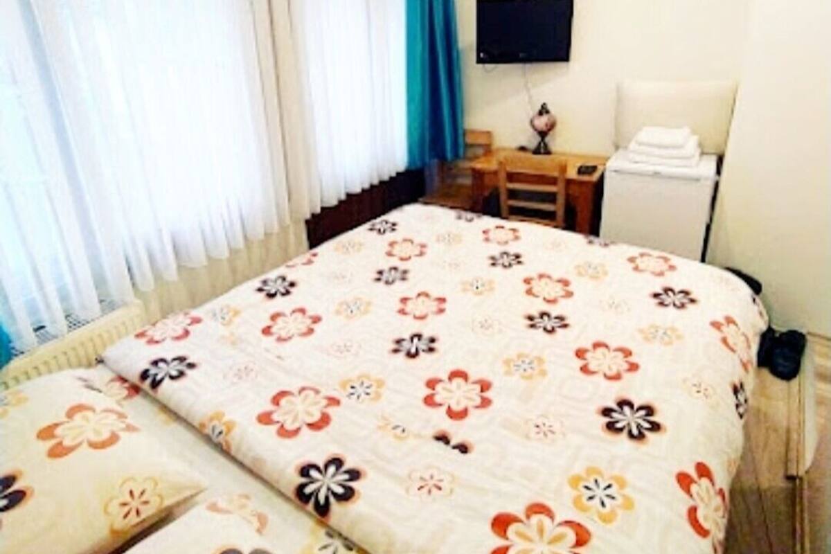 Habitació d'hotel amb llit, escriptori, cadira, televisió i aire condicionat.