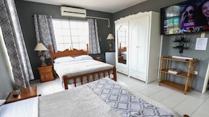 A bedroom with a bed, a TV, a wardrobe, and a bedside table.