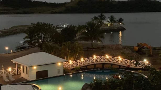 Un área de piscina con un puente, un edificio pequeño y un muelle con barcos.