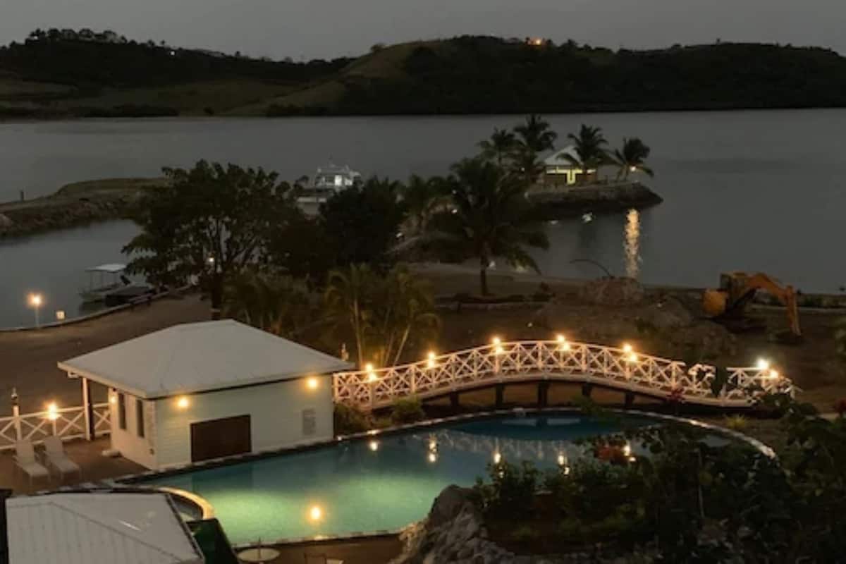 A pool area with a bridge, a small building, and a dock with boats.
