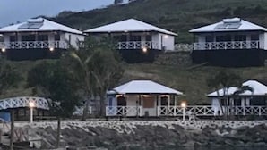 Un hotel costero con varias edificaciones de techos blancos, un muelle y una masa de agua tranquila.
