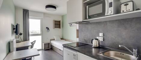 A modern kitchen with a built-in microwave, kettle, and sink.