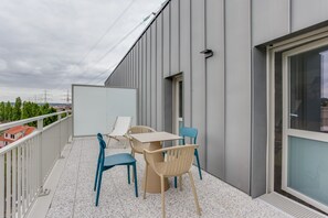 A balcony with a table and chairs, a whiteboard, and a view of the cityscape. - All Suites Appart Hôtel | Palaiseau - Massy TGV (Palaiseau)