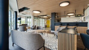 Un espacio lounge moderno con asientos, barra y ventanas amplias.