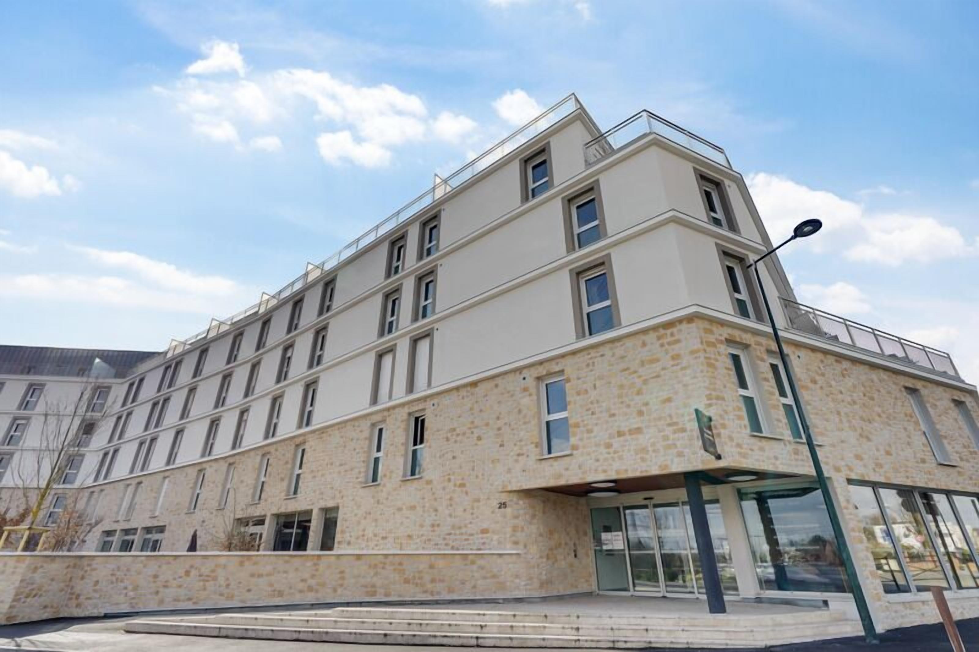 A modern multi-story building with a stone facade, large windows, and a flat roof.
