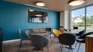 A modern interior with a blue wall, wooden ceiling, and large windows offering a view of the outside.