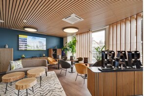 A modern lounge area with a wooden ceiling, a reception desk labeled "BAR", and a seating arrangement including sofas and chairs. - All Suites Appart Hôtel | Palaiseau - Massy TGV (Palaiseau)
