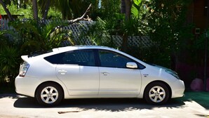 A white car parked in a driveway with a white fence and lush greenery in the background. - Absolute Beachfront Fiji (Nadi)