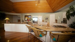 A modern kitchen with a central island, white cabinetry, and a wooden ceiling. - Absolute Beachfront Fiji (Nadi)