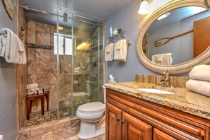 A bathroom with a glass-enclosed shower, a toilet, a vanity with a sink, and a large mirror. - Webb Cabin Mountain (Angel Fire)
