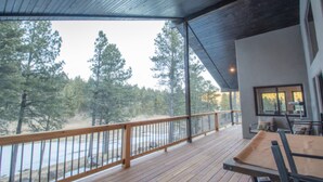 A wooden deck with a railing overlooking a forested area. - Lucky 8 Luxury Home (Angel Fire)