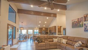 A spacious living area with a large sectional sofa, wooden flooring, and a ceiling fan. - Lucky 8 Luxury Home (Angel Fire)