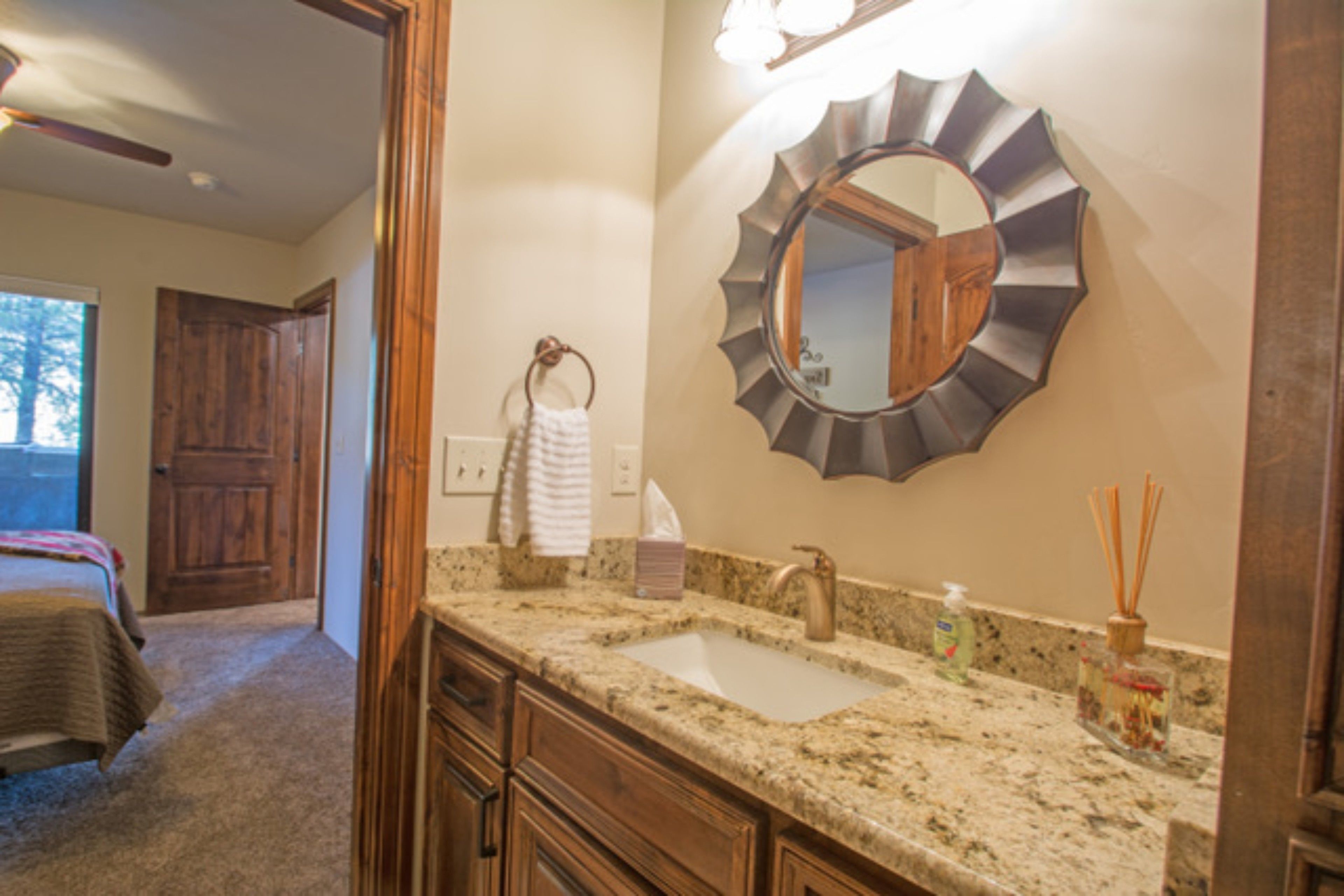 A bathroom with a granite countertop, a sink, a mirror, and a towel rack.