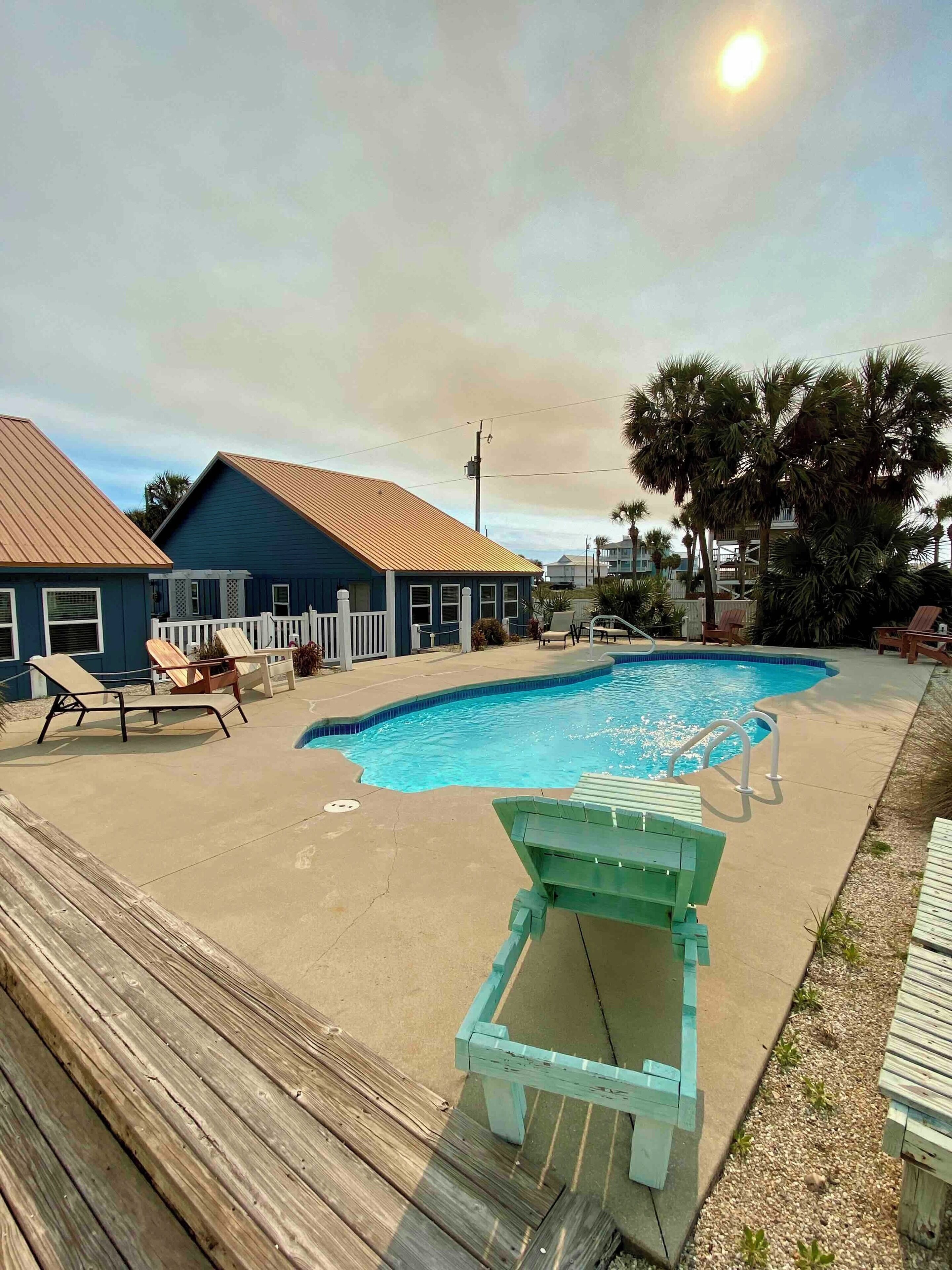 A swimming pool with lounge chairs and a wooden deck.