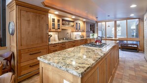 A spacious kitchen with wooden cabinets, granite countertops, and a large island.