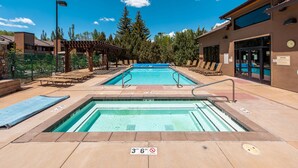 A pool area with two pools, lounge chairs, and a covered seating area.