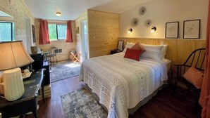 Une chambre confortable avec une tête de lit en bois, un grand lit avec une literie blanche, une table de chevet, une lampe et une chaise.