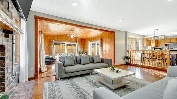 A spacious living room with a grey sofa, white coffee table, and patterned rug.
