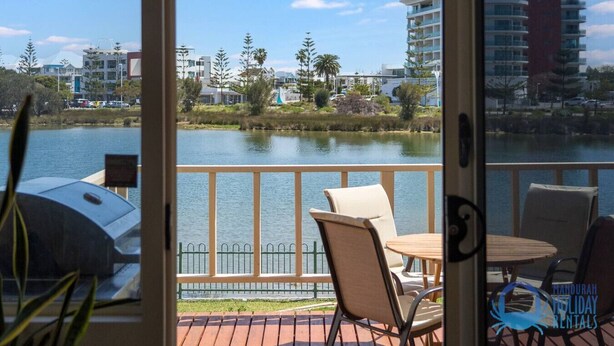 A balcony with a view of a lake, chairs, and a grill. - Mandurah Overlooking The Marina (Mandurah)