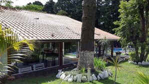 A house with a tiled roof, a glass-enclosed porch, and a swimming pool.