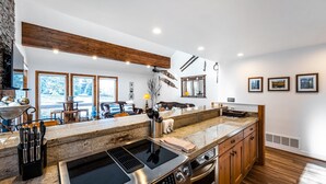 A modern kitchen with a large island, built-in oven, and a dining area with a view. - Exquisitely appointed-2BR+Loft-walk to Three Kings lift with private hot tub (Park City)