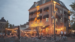 Een hotel met een opvallend bord, een terras en een gevel van baksteen.