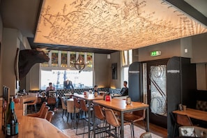 A restaurant interior with a map on the ceiling, wooden tables, and chairs. - Hanze Hotel Zwolle (Zwolle)