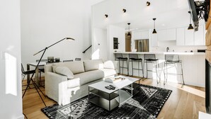 A modern living room with a sofa, coffee table, and a dining area with chairs and a table. - Stylish Park City 2BR, Walk to Three Kings Lift, Heated Pool & Hot Tub (Park City)