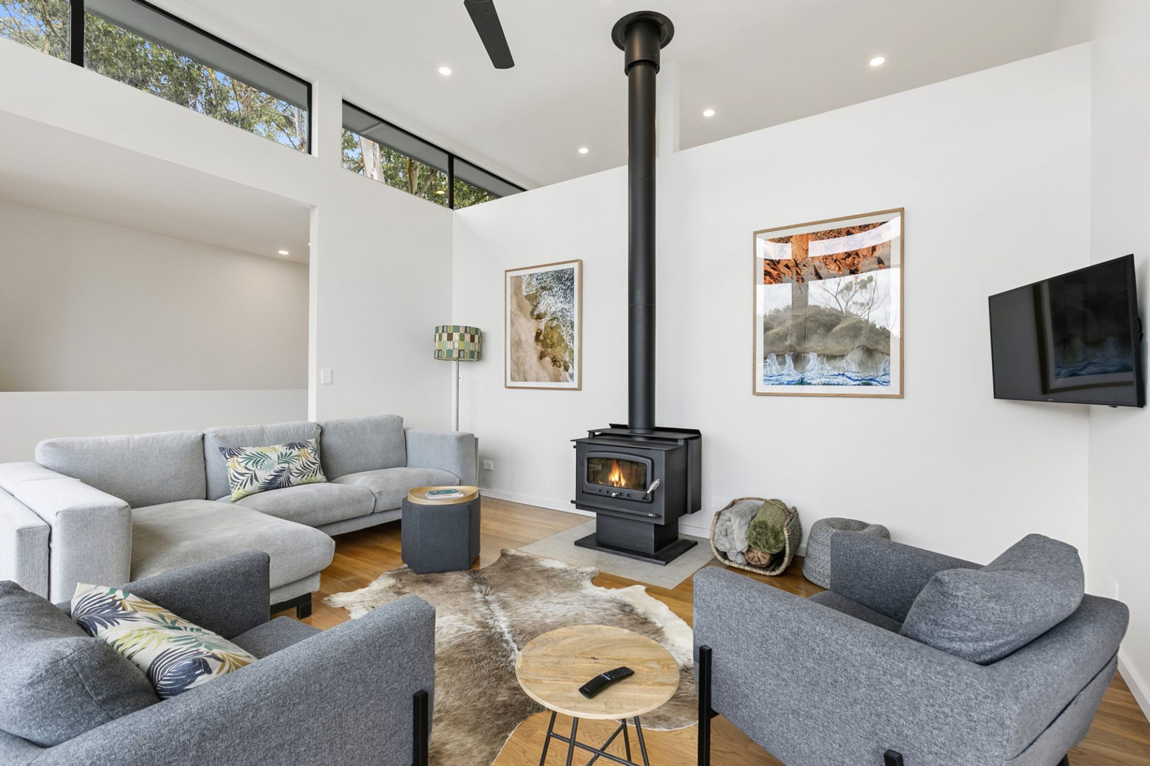 Ein modernes Wohnzimmer mit Kamin, grauen Sofas, einem Couchtisch und Kunstwerken an den Wänden.