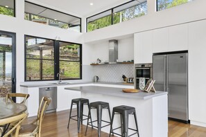Een moderne keuken met een groot eiland, barstoelen, een vaatwasser en een roestvrijstalen koelkast.