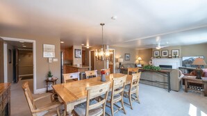 Une cuisine spacieuse dotée de meubles en bois, un coin repas avec une grande table en bois et des chaises assorties, et un salon confortable avec une cheminée et des sièges confortables.