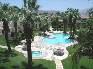 Ein Resort mit großem Schwimmbecken, umgeben von Palmen und Liegestühlen.