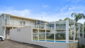 A modern building with a glass-enclosed pool area, a "No Parking" sign, and a white car parked nearby. - The Sands, Unit 5 - The Entrance, NSW (The Entrance)