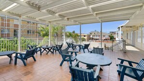 An outdoor patio with tables and chairs, a covered area, and a view of buildings and greenery. - The Sands, Unit 5 - The Entrance, NSW (The Entrance)