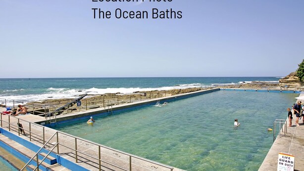 A large outdoor swimming pool with clear blue water, surrounded by a rocky shoreline and a lifeguard on duty sign. - The Sands, Unit 5 - The Entrance, NSW (The Entrance)
