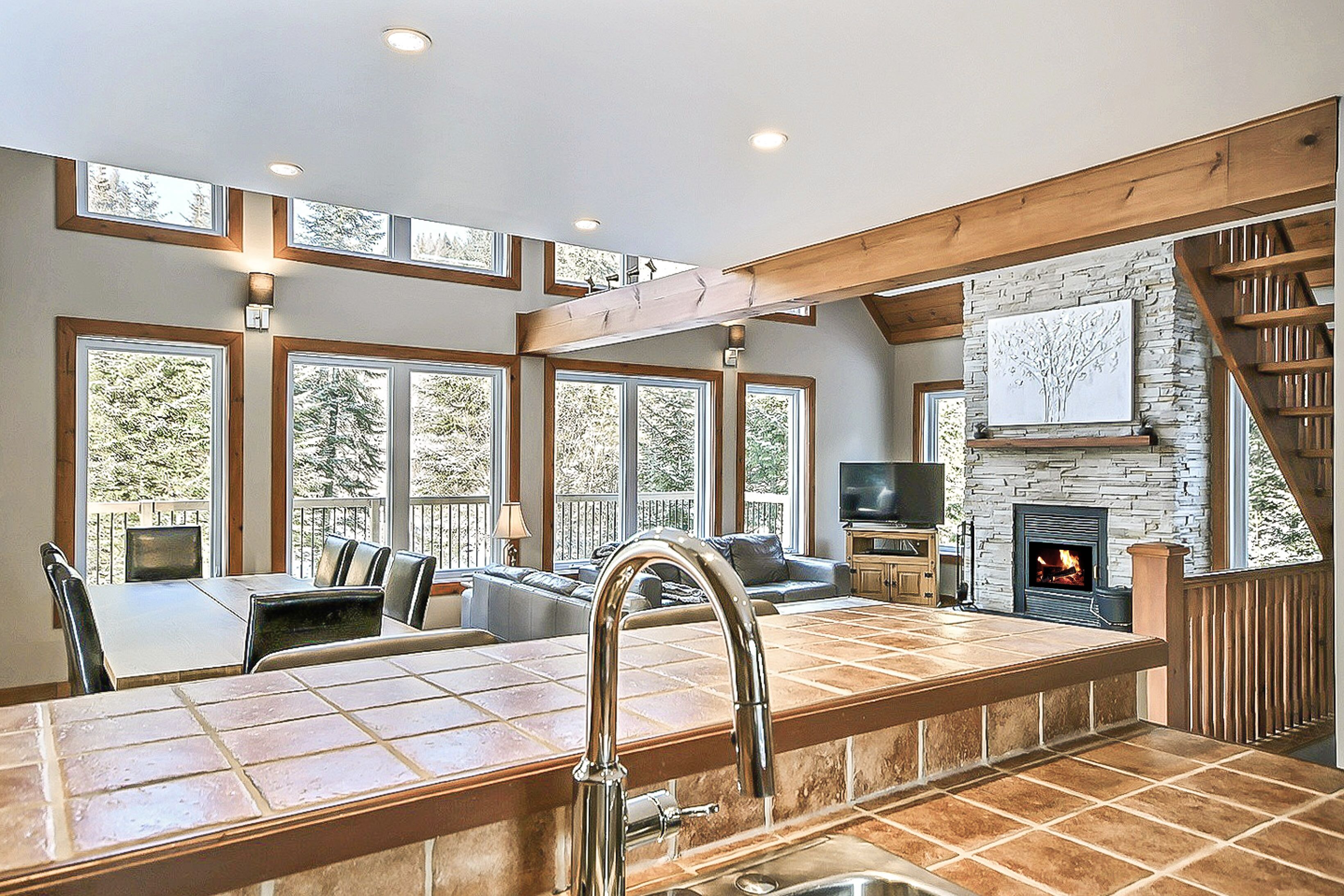 A spacious kitchen with a large island, a stone fireplace, and a dining area with a view of the outdoors.