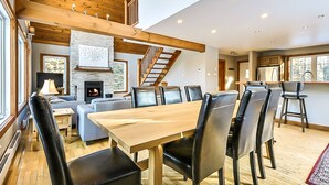 Amplia sala de estar con chimenea, techo de madera y una mesa de comedor con sillas.