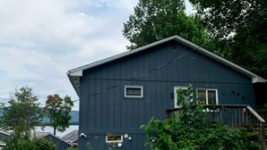 Une maison à deux étages, à la façade bleu foncé, avec un petit porche doté d’une balustrade en bois et le numéro « 10 » bien visible sur le côté.