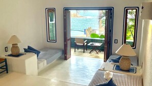A room with a view of the sea, a table with chairs, and a sofa with lamps. - Exclusive Villa with Private Beach and Beautiful  Views to the Pacific Ocean (Bahías de Huatulco)