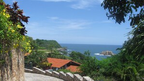A stone staircase leading to a coastal area with a view of the ocean and a red-roofed building. - Exclusive Villa with Private Beach and Beautiful  Views to the Pacific Ocean (Bahías de Huatulco)