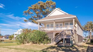A two-story house with a balcony and a staircase leading to the second floor. - Sunset Joy - KDH MP 6, Soundfront, Sound View, Kayak, Community Boat Ramp, Pets OK, Flex Stays (Kill Devil Hills)