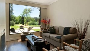 En moderne stue med et stort vindue, en sofa, et sofabord og en pejs.