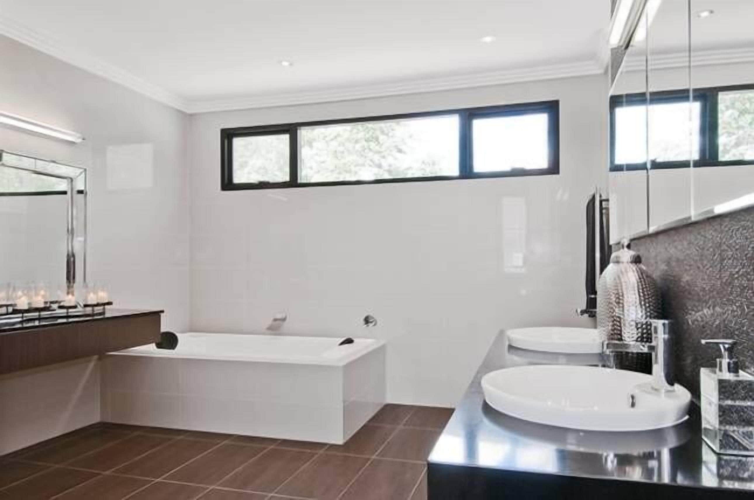 A modern bathroom with a freestanding bathtub, a vanity with a sink, and a large mirror.