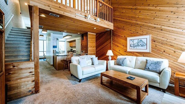 A spacious living area with a wooden staircase, a dining area, and a kitchen in the background. - Nostalgic Park City 2BR+Loft-Gas Fireplace-Walk to Park City Resort-In Unit W/D (Park City)