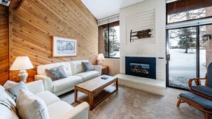 A modern living room with a fireplace, wooden walls, and a large window. - Nostalgic Park City 2BR+Loft-Gas Fireplace-Walk to Park City Resort-In Unit W/D (Park City)