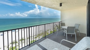 A balcony with a view of the ocean, a table with chairs, and a railing. - Seawinds 801-Beachfront Condominium with Unbeatable Gulf front Views from Oversized Balcony! (Marco Island)