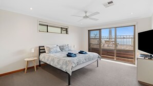 A bedroom with a bed, a nightstand, a TV, and a balcony with a view.